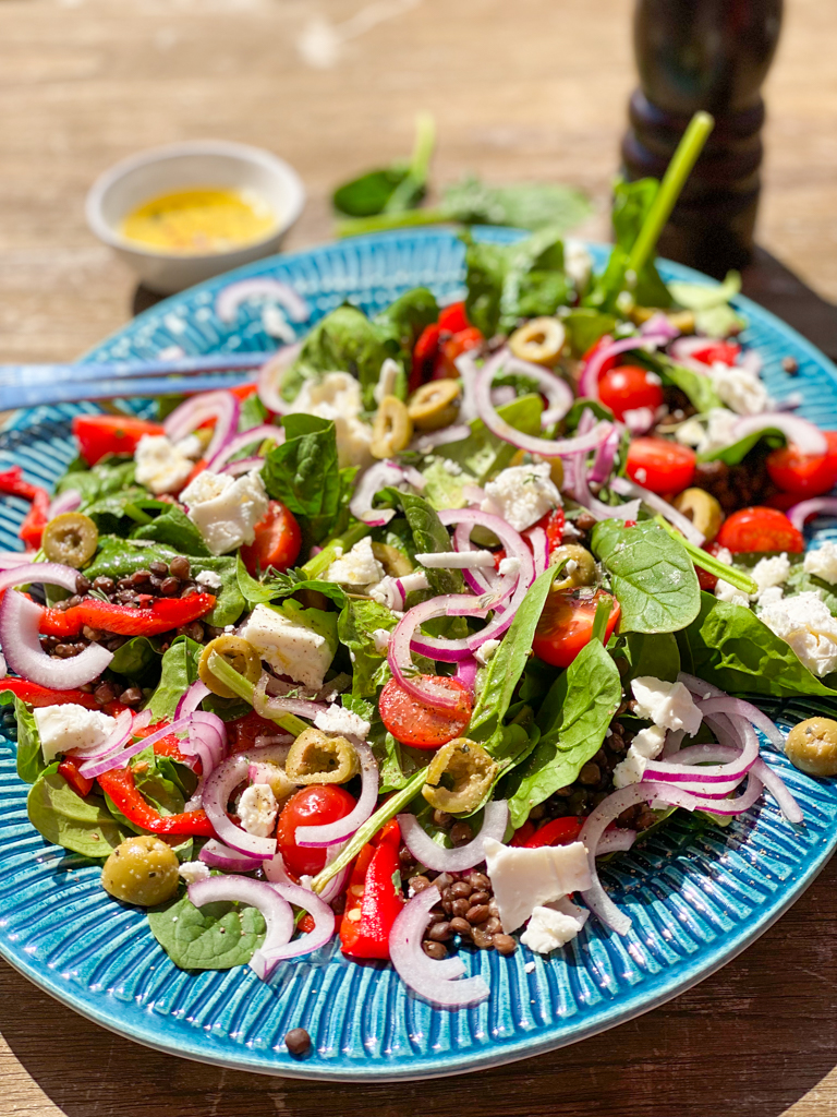 zomerse Griekse salade met linzen olijven, rode ui, tomaten en spinazie